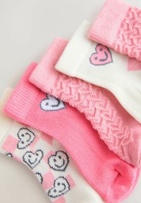 Quatre paires de chaussettes comportant des couleurs rose et blanche, divers motifs de cœurs, une texture côtelée et un motif à damier.