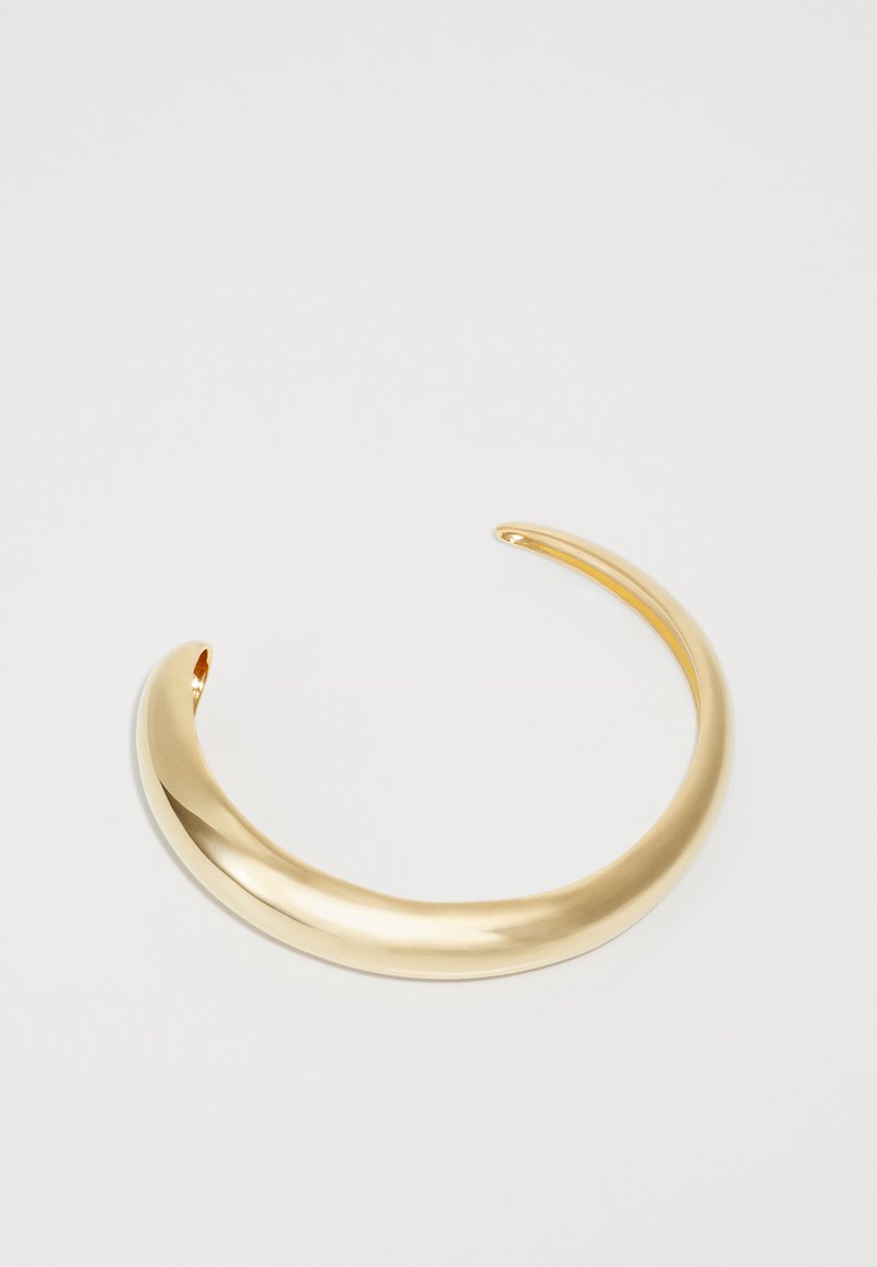 Náhrdelník z kovu v zlatej farbe s hladkým, odrazovým povrchom a minimalistickým dizajnom, ktorý má jemne zaoblené okraje a otvorené konce.