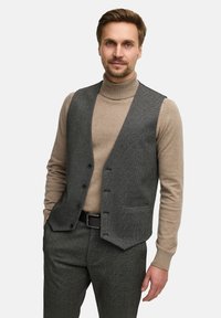 Grå hundetand vest med fem knapper, båret over en beige turtle neck. Outfitet har en skræddersyet pasform og subtil tekstur.