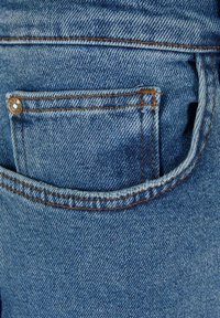 Denim tkanina v svetlo modri barvi, z majhnim sprednjim žepom z zlatim okovjem. Šivanje v kontrastni oranžni barvi dodaja podrobnosti.