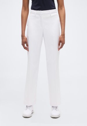 Fehér, egyenes szárú, szabott nadrág sima textúrával és finom elejű redőkkel, fehér golfcipővel párosítva.