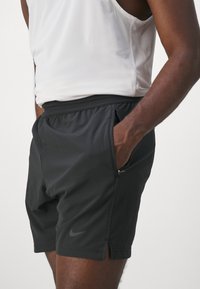 Shorts de sport noirs avec une surface texturée, une taille élastique et des poches latérales. Présente un petit logo Nike sur la jambe gauche.