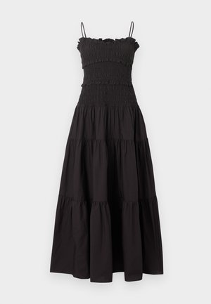 Robe maxi noire sans manches avec corsage froncé, bord supérieur à volants, jupe à étages et fines bretelles sur fond neutre.