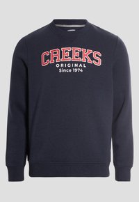 Sudadera azul marino con cuello redondo, puños y dobladillo acanalados. Presenta el texto "CREEKS ORIGINAL" en blanco y rojo, con "Desde 1974" debajo.