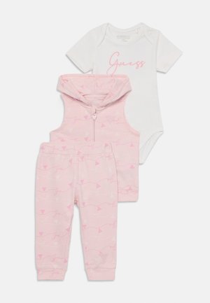 Completo per neonati in tre pezzi che include un body bianco a maniche corte, un gilet con cappuccio rosa con un motivo ripetuto "Guess", e pantaloni coordinati.