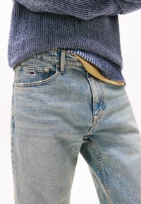 Lichtblauwe denim jeans met een vervaagd textuur, voorzien van een klein logo op de achterzak en een standaard pasvorm. In combinatie met een gebreid trui.