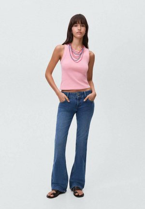 Top rosa ajustat, blugi evazați albaștri, sandale negre. Accesoriile includ coliere din mărgele stratificate în roșu și albastru. Design simplu, look casual.