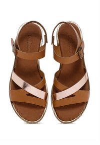 Sandali in pelle marrone chiaro con design a fascia incrociata, accentuati da dettagli in rosa oro metallico e suola texturizzata. Include una fibbia regolabile per una vestibilità ottimale.