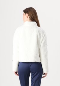 Weiße Fleecejacke mit hohem Kragen und kurzer Passform. Verfügt über lange Ärmel und dekorative Akzente an den Bündchen. Weicher Stoff.