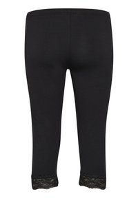 Leggings noirs avec une texture lisse, ornés de dentelle au niveau du mollet, et d'une taille élastique pour un maintien sécurisé.