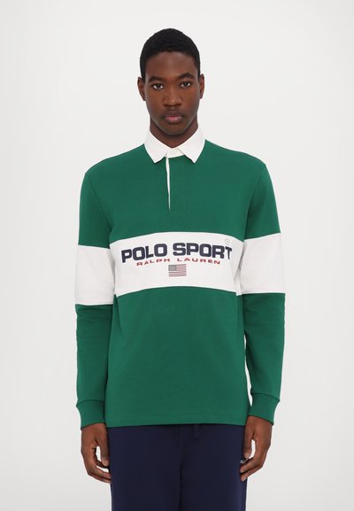 Långärmad polo i mörkgrön med vit horisontell rand. Har "POLO SPORT"-logotyp, accentfärger och knäppt krage.