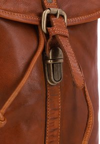 Sac en cuir marron avec fermoir de style vintage, présentant une surface texturée, des accents cousus et une bandoulière lisse pour une fermeture sécurisée.