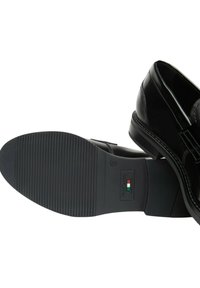 Scarpe da donna nere in vernice con finitura liscia, suola in gomma con scanalature orizzontali e un'etichetta del marchio discreta sul fondo.