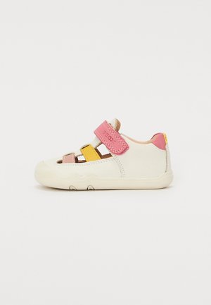 Hvit sneakersko med rosa, gul og beige aksenter. Har borrelåsrem, åpne sider og en teksturert gummisåle.