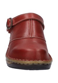 Red leather clog with a round toe, featuring a strap and metal buckle, stitched detailing, and a textured sole.