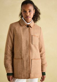 Brown houndstooth pattern jacket with a collar, front button closure, and two front pockets. Accented with a contrasting trim and texture.
