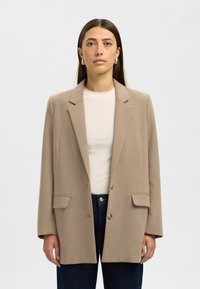 Beige tailored blazer made of a smooth fabric, featuring a notched lapel, two front pockets, and a single button closure.