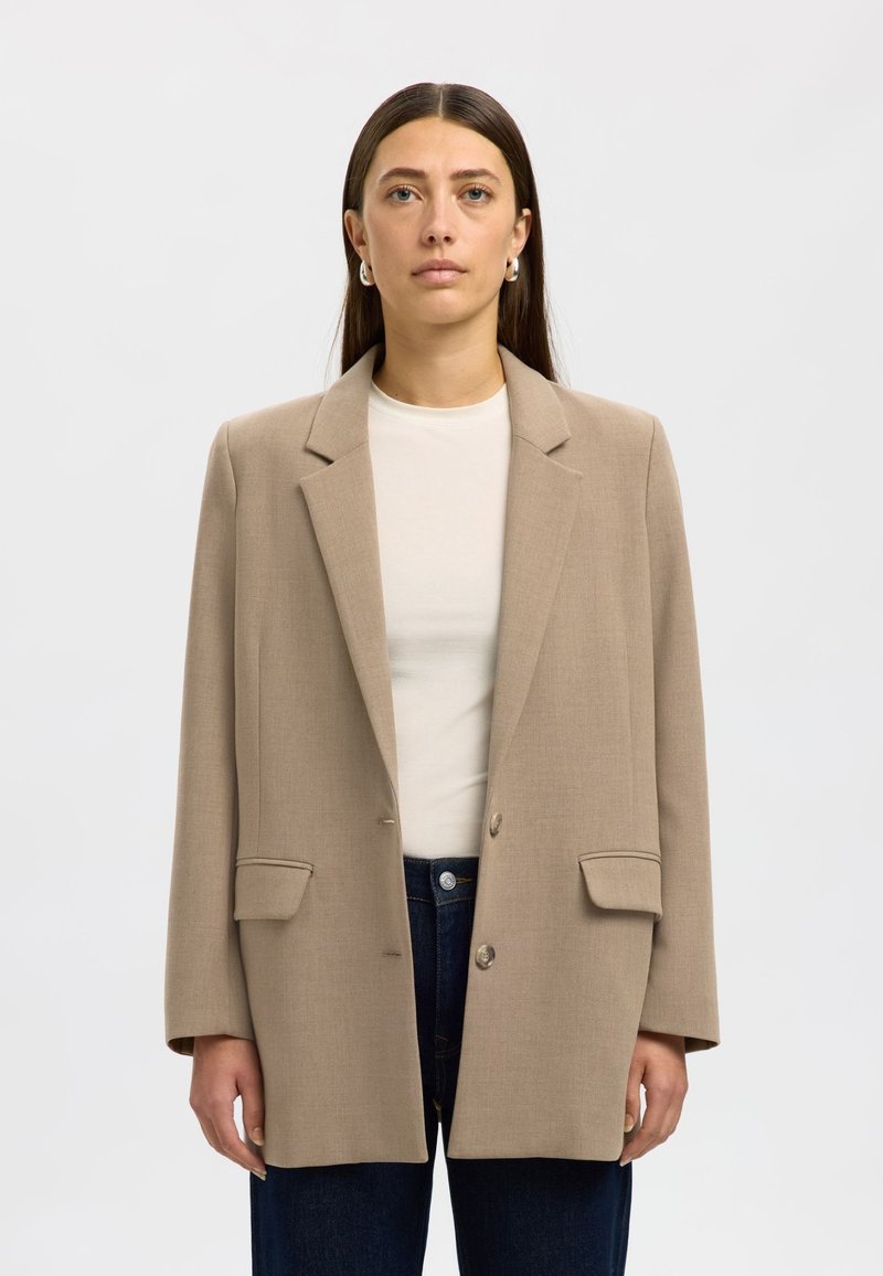 Beige tailored blazer made of a smooth fabric, featuring a notched lapel, two front pockets, and a single button closure.
