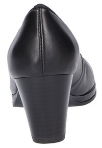 High-heeled black leather shoe with a rounded toe, smooth texture, and a moderate block heel. Stitching detailed along the back seam.