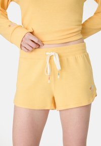 Shorts gialli in cotone con vita elasticizzata, coulisse con punte multicolori e delicata ricamatura floreale sui lati.
