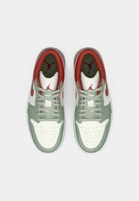 Une paire de sneakers Nike Air Jordan verts, blancs et rouges vue de dessus sur un fond blanc.