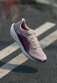 Baskets rose clair avec tige en maille et accents bleu foncé. Présente un logo rose, une semelle texturée et un système de laçage.