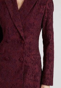 Bordeauxcoloured blazer met een getextureerd bloemmotief, dubbel geknoopte ontwerp, gelapte revers en twee zakken aan de voorkant. Zachte stof met accenten.