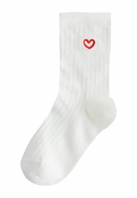Balta ribota zeķe ar nelielu sarkanu sirds emblēmu izšūtu netālu no augšējās aproces.