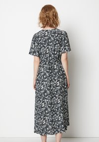 Abito floreale in bianco e nero con maniche corte, vita elastica e design lungo fino alla caviglia. Tessuto morbido e vestibilità ampia.
