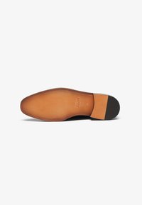 Bruine leren schoenen zool met een gladde tan afwerking. Bevat een lichte kromming, afgewerkte stiksels, en een zwarte rubberen hakaccent.
