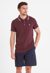 Burgundy polo shirt with white accents, three-button placket, and logo. Paired with navy cargo shorts featuring side pockets.