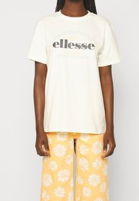 Weißes Baumwoll-T-Shirt mit kurzen Ärmeln und Rundhalsausschnitt. Mit "ellesse"-Logo in Dunkelgrau und Akzenten in Grün und Orange.