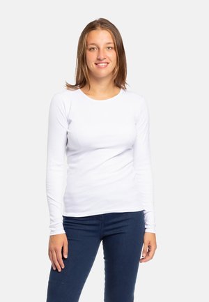 Maglietta bianca in cotone a maniche lunghe con scollo rotondo, indossata con jeans blu scuro, caratterizzata da un design aderente e una trama liscia.