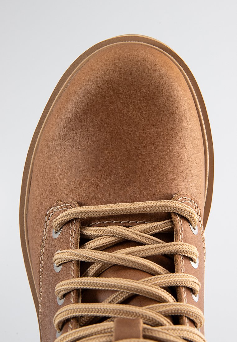 Braunlederstiefel mit einer runden Zehenform, beigen Schnürsenkeln, Metallösen und einer glatten Textur, die das strapazierfähige Design und die Konstruktionsdetails präsentieren.