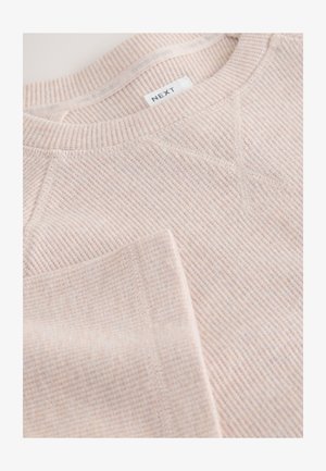 Light pink ribbed sweatshirt with crew neck, stitching details, and label reading "NEXT." Soft texture with subtle pattern throughout.