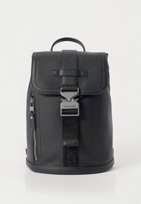 Mochila em pele preta com design estruturado, aba superior, ferragens prateadas, bolso frontal com fecho de correr e detalhe com logo na alça.