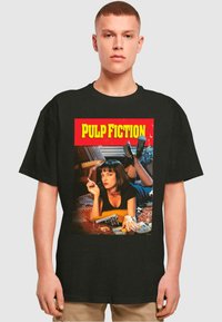 Svart bomull t-skjorte med grafisk trykk av "Pulp Fiction" med retrodesign, livlige røde og gule farger, og detaljert bilde.