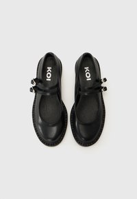 Black leather Mary Jane shoes with two adjustable straps, rounded toe, textured insole, and a ribbed rubber sole. Brand label visible inside.