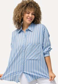 Hellblau gestreiftes Button-Up-Hemd mit lockerer Passform, Fronttasche und hochgekrempelten Ärmeln. Weiche Textur und glattes Material.