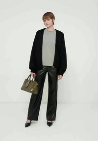 Juoda megzta kardiganė, pilka palaidinė ir blizgios juodos pločio kelnios. Alyvuogių žalumo rankinė su žvaigždės detalė. Juodi smailūs batai. Paprastas fonas.