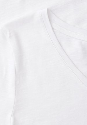 Witte katoenen V-hals T-shirt stof en stikseldetail van dichtbij, met nadruk op textuur en naadlijnen.