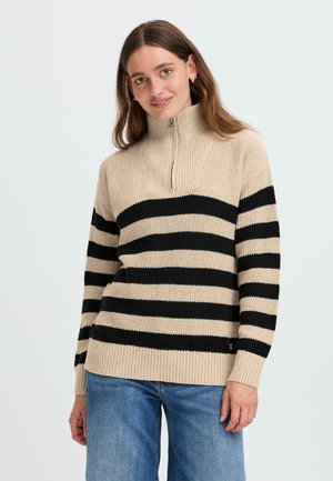 Beige og svart stripete genser med høy krage, halv glidelås, ribbestruktur og lange ermer. Stoffet ser mykt og strikket ut.