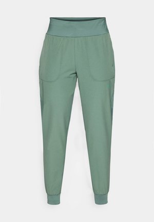 Zielone spodnie sportowe z szerokim pasem, elastycznymi mankietami i dwiema bocznymi kieszeniami. Gładka faktura, zwężający się krój i minimalne detale szycia.
