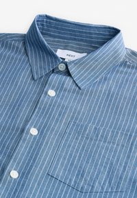 Camicia a righe blu con bottoni, realizzata in cotone, con collo classico, bottoni bianchi e taschino sul petto.