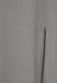 Tissu ribbed gris avec une texture douce. Présente un motif à rayures verticales et un détail d'ouverture sur le côté pour un intérêt de design supplémentaire.