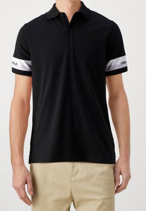 Zwarte polo shirt van katoen. Beschikt over een klassieke kraag, een drieknopenlijst en contrasterende gestreepte mouwen met logo-accenten.