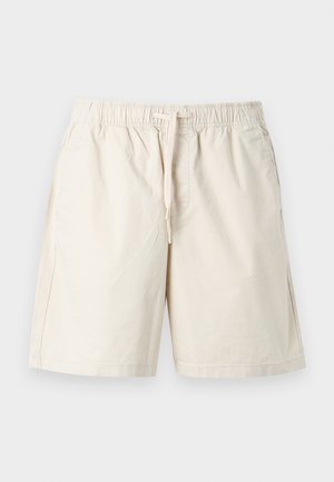 Beige elastic waist shorts with drawstring, front pockets, and knee-length cut on a plain light background.
