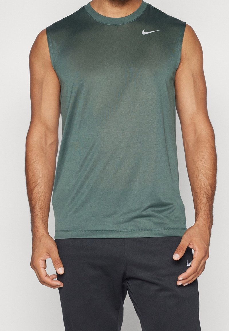 Débardeur de sport en tissu vert foncé. Doté d'un col rond et d'un logo Nike blanc sur le côté gauche de la poitrine. Texture douce et évacuant l'humidité.