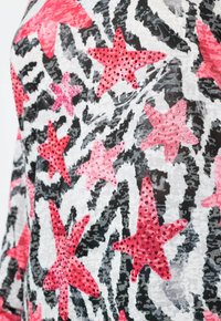Zwart-witte abstracte patroonstof met helderpaarse sterrenvormen, versierd met kleine rhinestones.