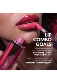 Person påfører knallrosa lipgloss på leppene, holder en KIKO Milano 3D Hydra Xtreme Lipgloss tube med applikator.